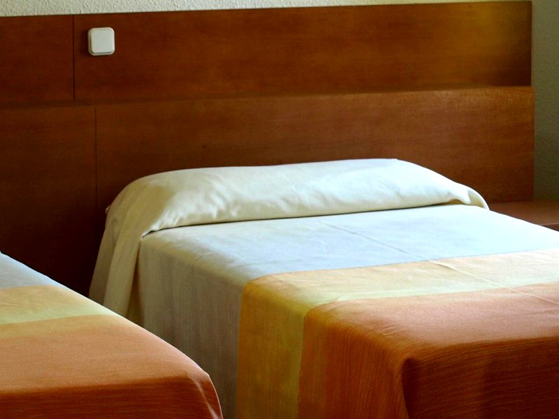 Habitación doble con dos camas y cabecero de madera en la Residencia Universitaria San Ildefonso, Alcalá de Henares