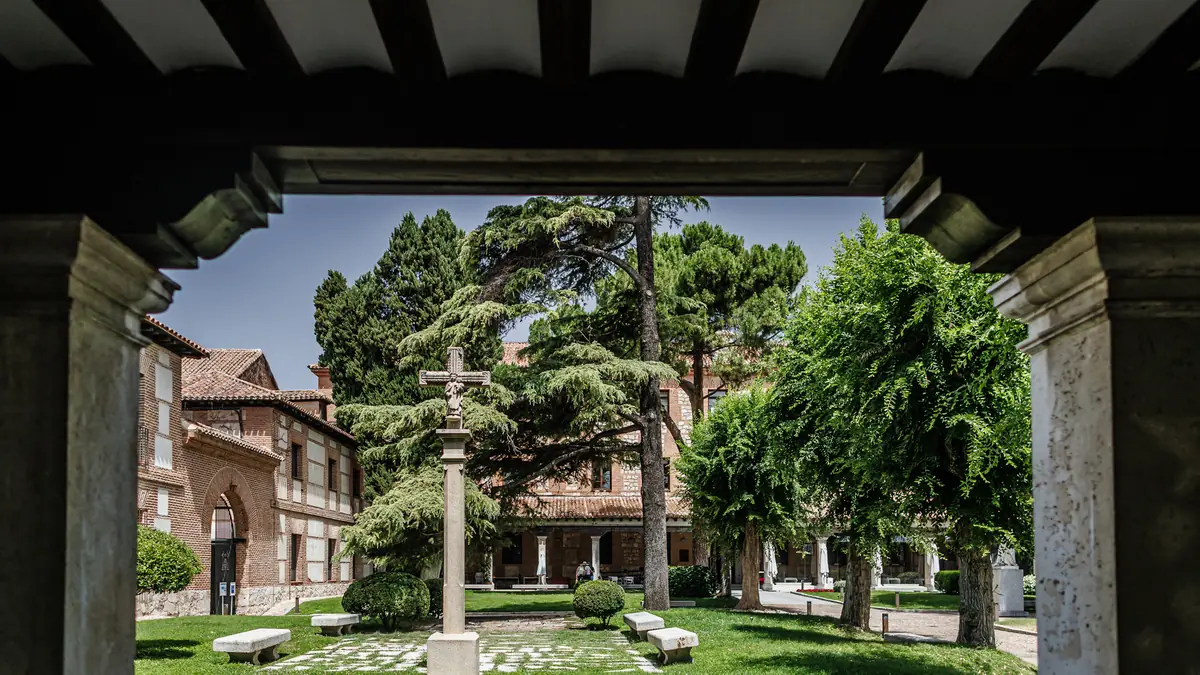 Patio del Colegio Mayor de San Ildefonso visto desde la arcada, con el monumento central y los cedros