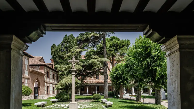 Patio del Colegio Mayor de San Ildefonso visto desde la arcada, con el monumento central y los cedros