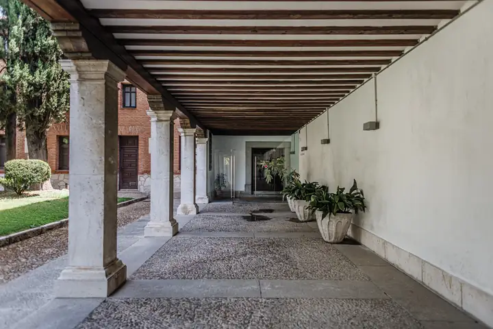 Galería porticada con columnas de piedra y suelo empedrado abierta al jardín interior