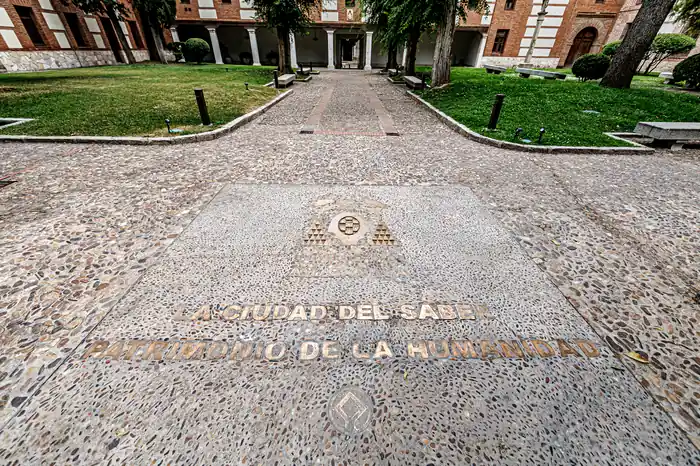 Patio empedrado con la inscripción «La ciudad del saber · Patrimonio de la Humanidad» de Alcalá de Henares