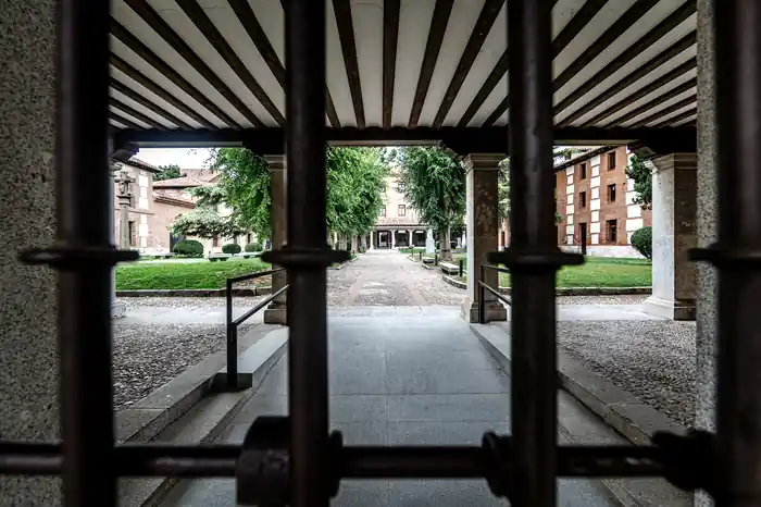 Jardín simétrico con paseo central y cipreses visto desde una galería porticada del colegio