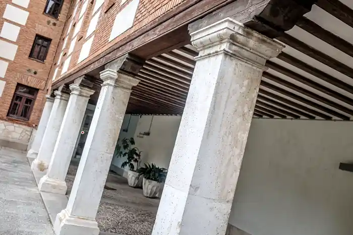 Columnas de piedra y techumbre de vigas de madera de una galería porticada del colegio